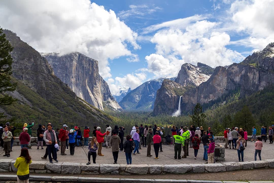 Tourists enjoying the scenic landscape of mountains and waterfalls in Yosemite National Park, United States.